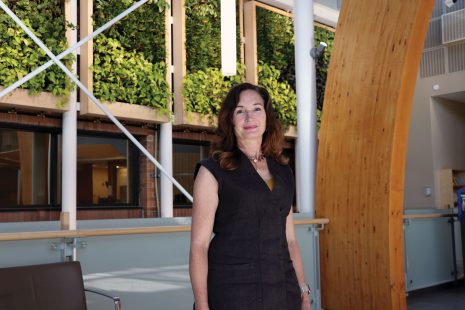 Image shows woman with long brown hair standing in the College's foyer