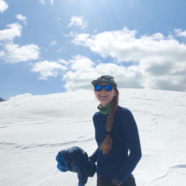 Image shows woman outdoors in a snowy landscape, smiling at the camera.