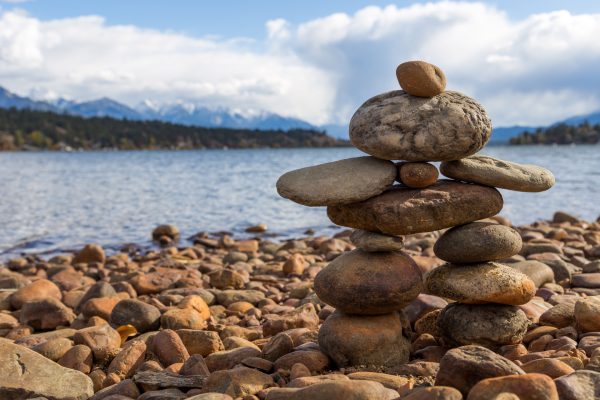 Image shows inukshuk made of rocks along a rocky beach.