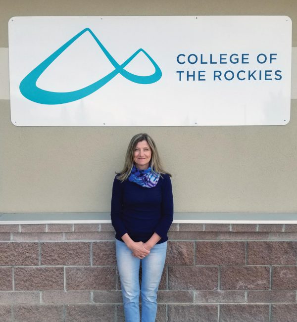 College of the Rockies Invermere campus' acting manager, Michelle Taylor, smiles at camera below College sign.