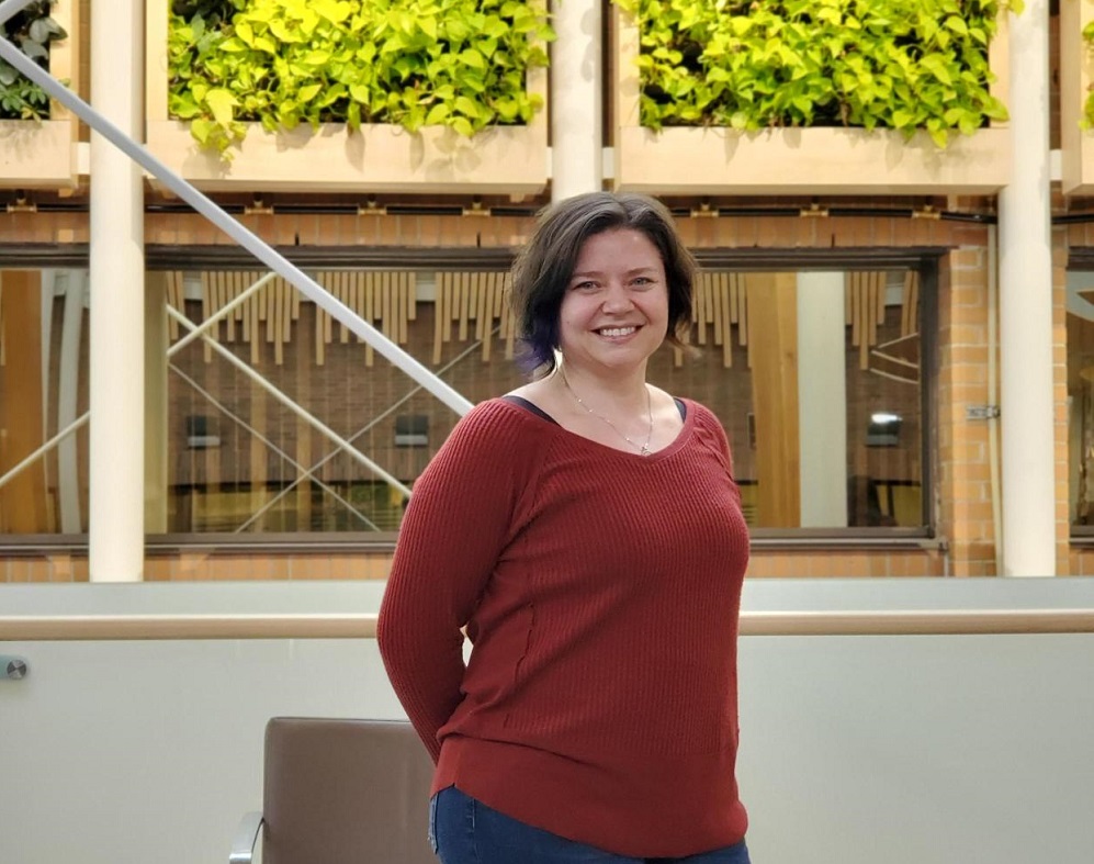 A college instructor standing in front of a living wall.