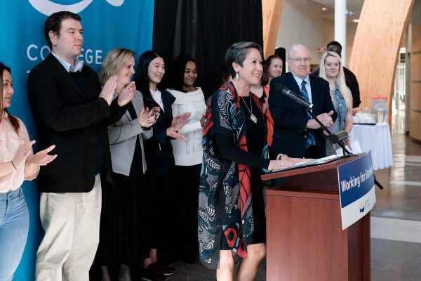 Image of Minster of Advanced Education, Skills and Training, Melanie Mark, with a group of people standing behind her applauding