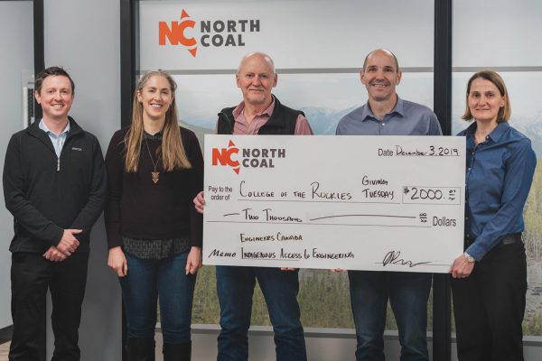 Image shows five people beneath a North Coal sign, with three holding a large cheque.
