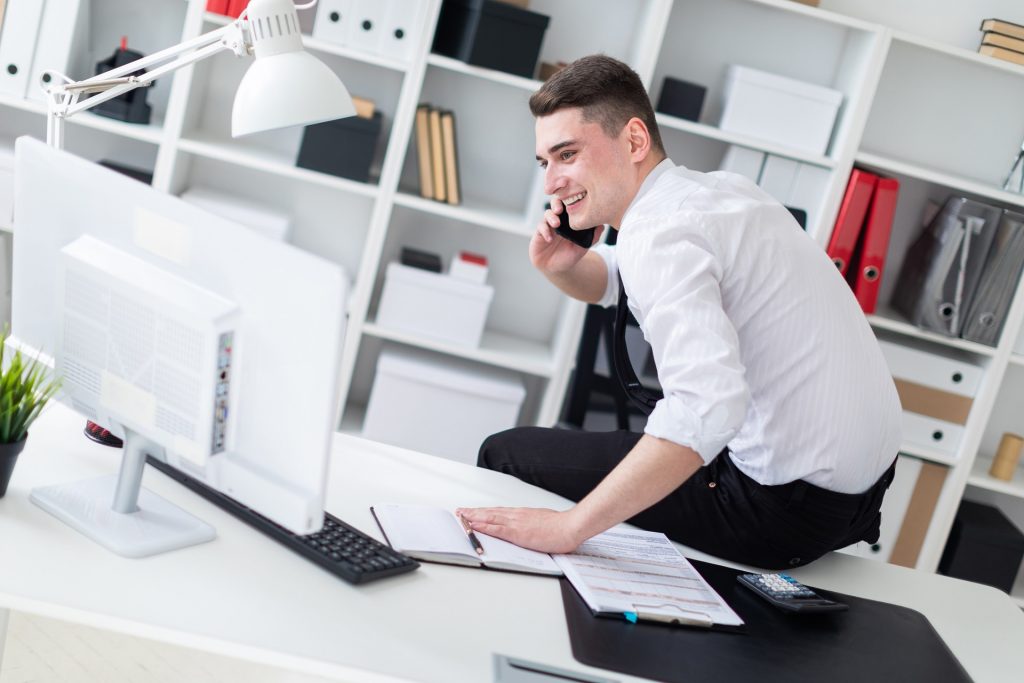 Charming young man working in a bright office. Young man in white shirt with black tie and black trousers. photo with depth of field