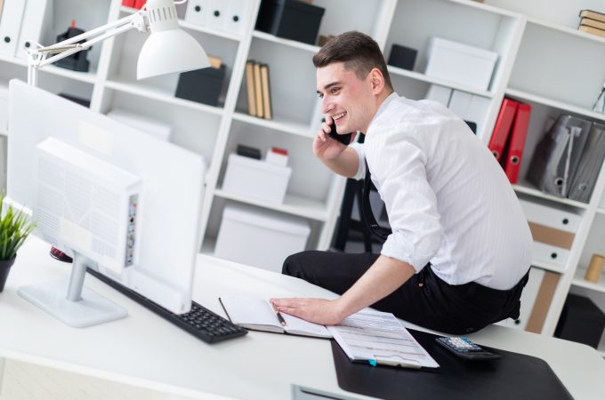 Charming young man working in a bright office. Young man in white shirt with black tie and black trousers. photo with depth of field