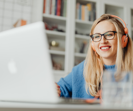 Image shows woman looking at laptop and smiling.