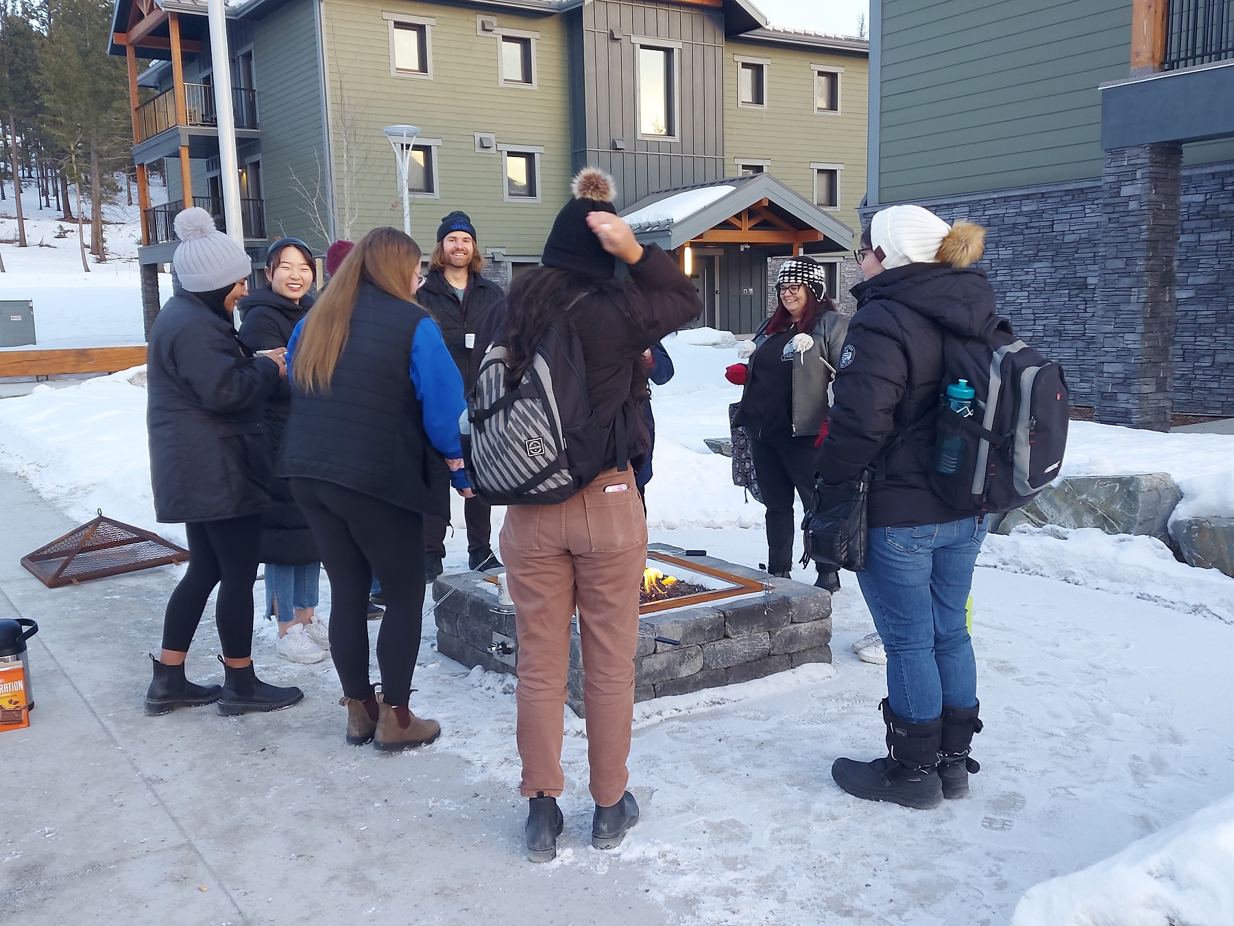 Group of student mentors and students gathered around campfire.