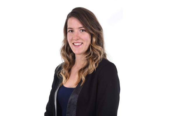 Image shows professional headshot of woman with long hair smiling at the camera.