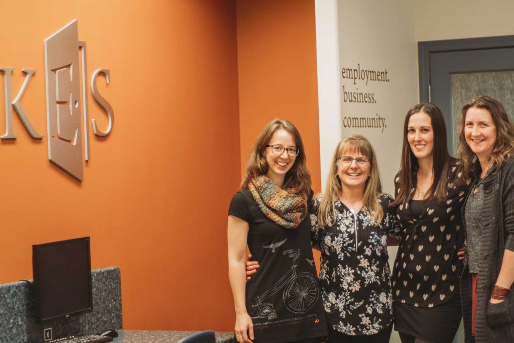 An image of four females standing together inside an office.