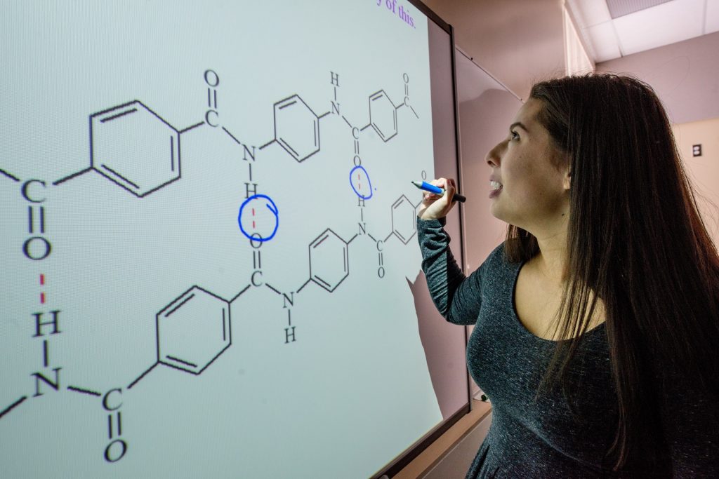 Student working on chemical equation on whiteboard