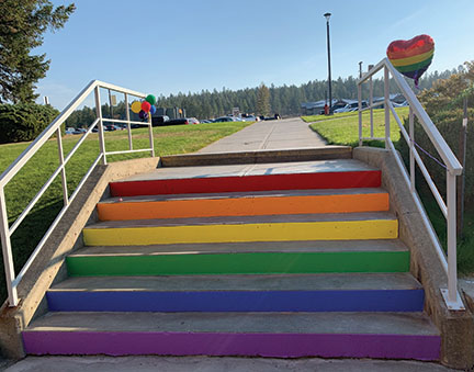Image shows a flight of stairs outside of College of the Rockies, painted in pride colours.