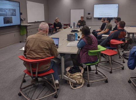 Image shows group of individuals meeting around a large table.