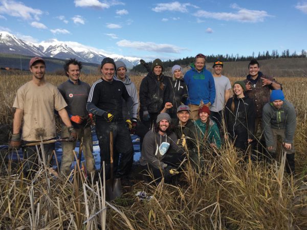 Image shows group of students in marshy area with mountains in the background.