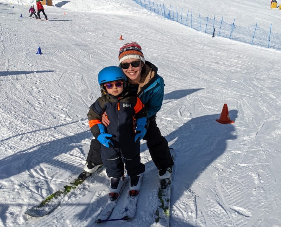 Woman crouching with child on a ski hill.