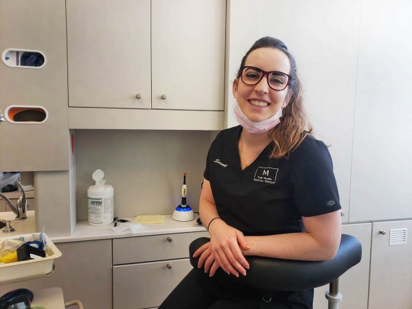 Image of young woman in glasses and scrubs in a dental office.