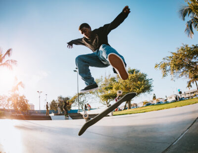 A skateboarder in LA, California rides at a skatepark, attempting an assortment of flip tricks and grinds. Youth culture and skill in extreme sports.