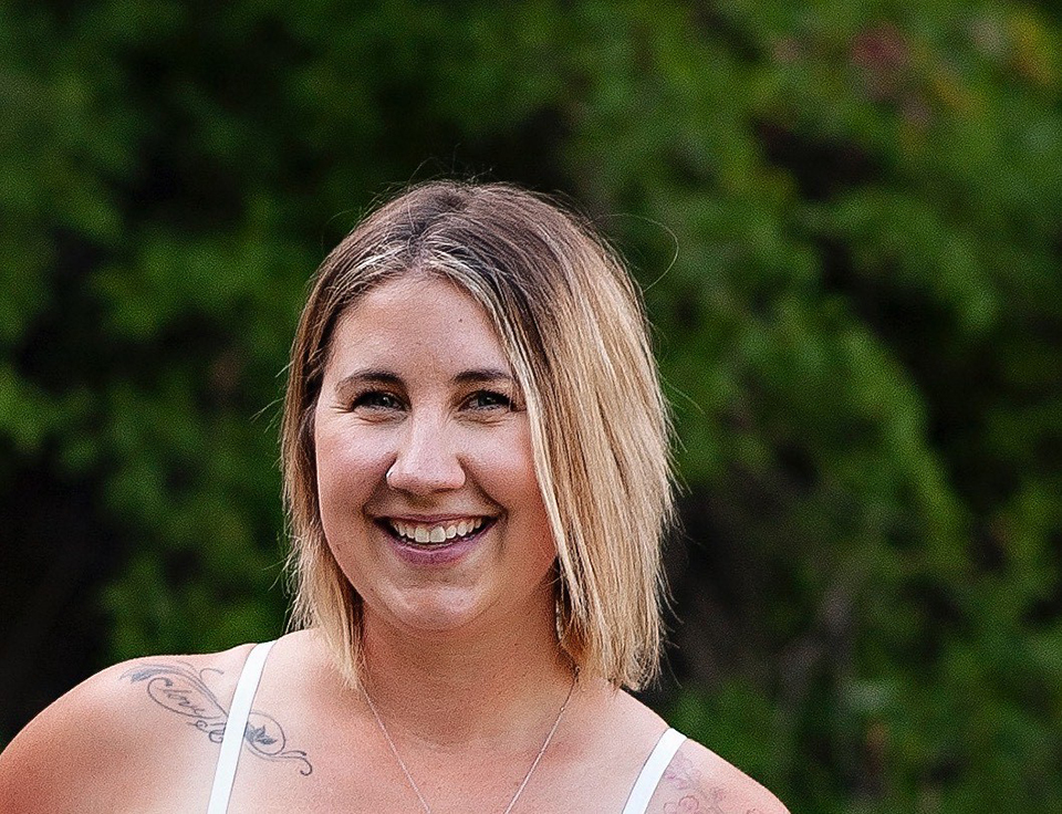 Image shows smiling woman with trees in the background.