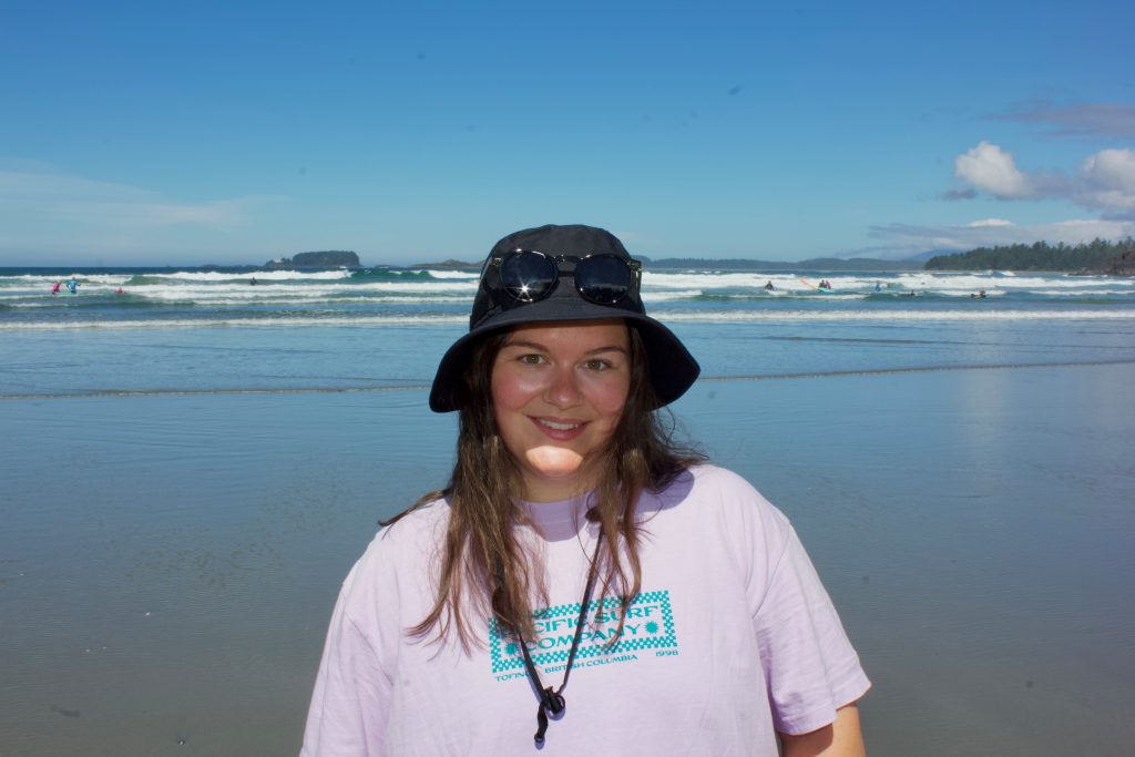 Image shows woman in a sun hat in front of a large body of water.