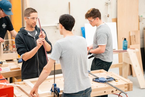 Image show instructor teaching students in a woodworking shop.