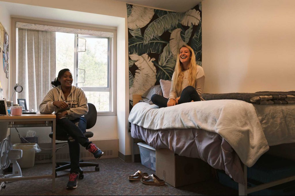 An image of a bedroom with two girls chatting at the College of the Rockies' Student Residence.