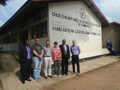Image shows group of people standing in front of building in Tanzania.
