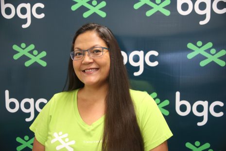 Image shows woman with long dark hair and glasses smiling at the camera