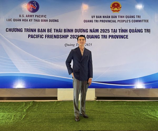 Image shows man standing in front of an awards banner