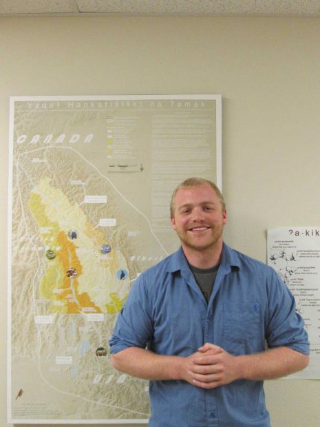 Image of man smiling at camera in front of a map.