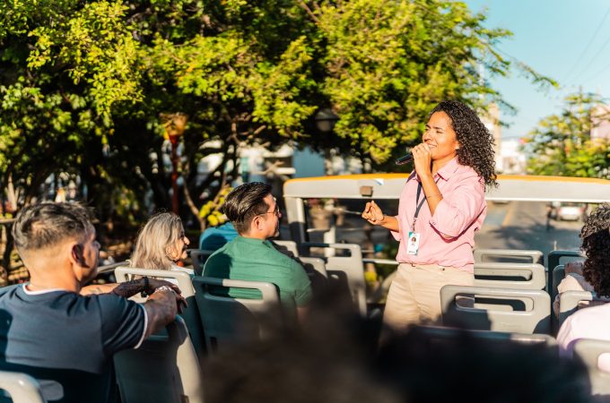 Mid adult tourist guide woman talking with tourist on tour bus