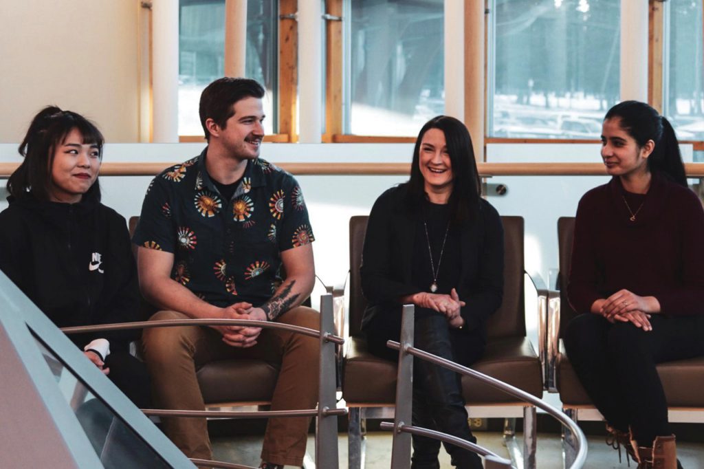 Image shows four Tourism Mangement students sitting in College lounge and smiling.