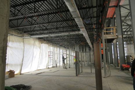 Image shows trades workers working inside building as it is being constructed.