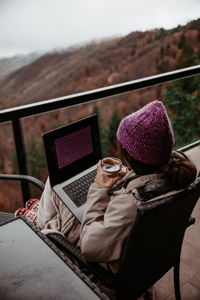 Young woman watching session on laptop with mountains in background