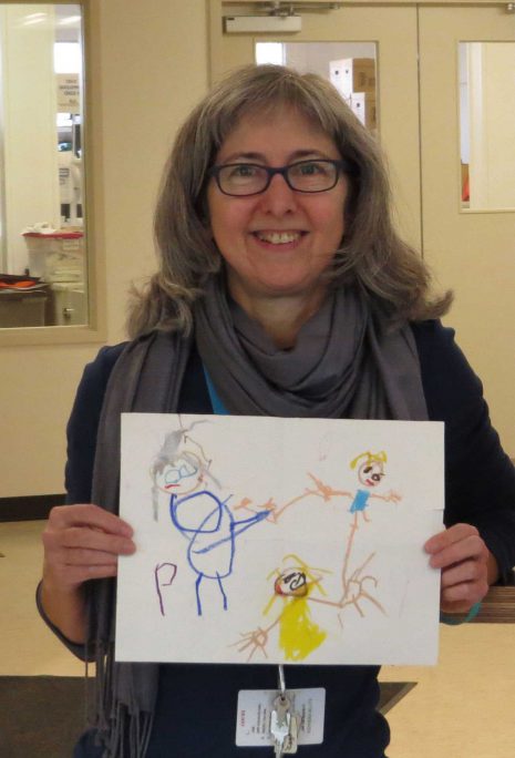 image of woman in glasses holding a child's drawing.