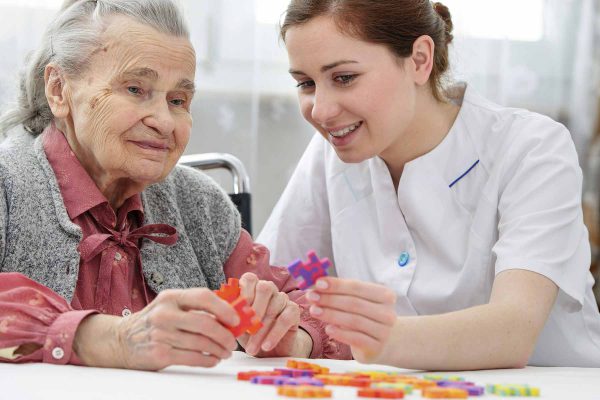 Image of an activity assistant doing puzzle with elderly resident.