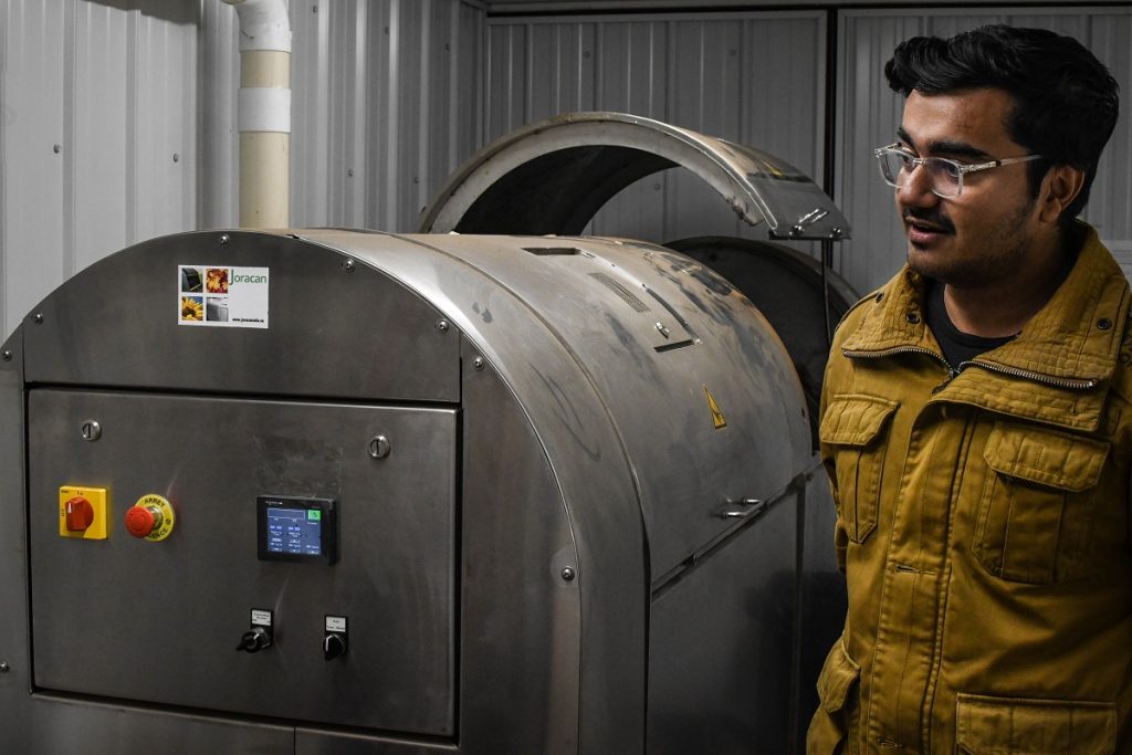 A student standing next to a food composter.