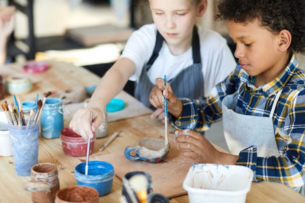 Two young children painting pottery.