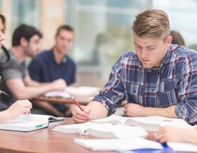 Young man studying with group of other students in background