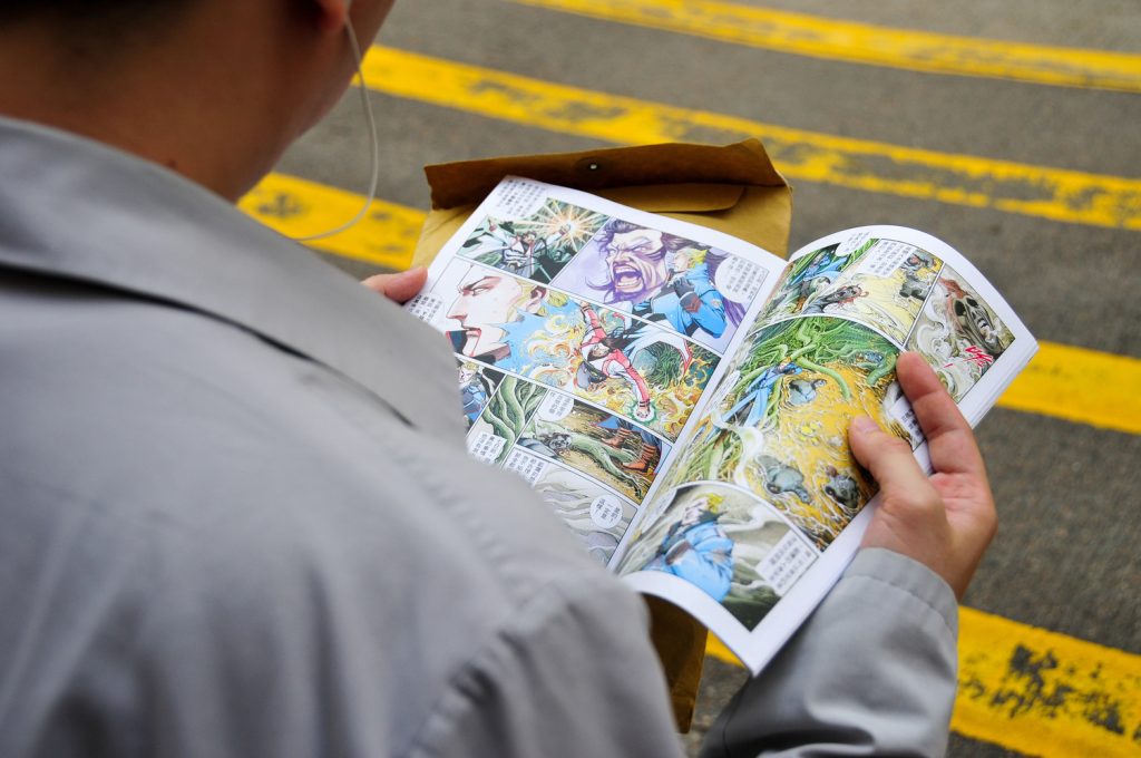 Man reading a cartoon on a city street