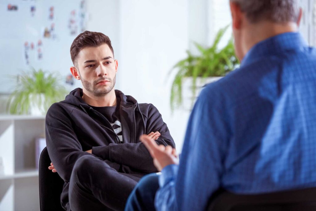 Young man seated having a discussion with a counsellor.