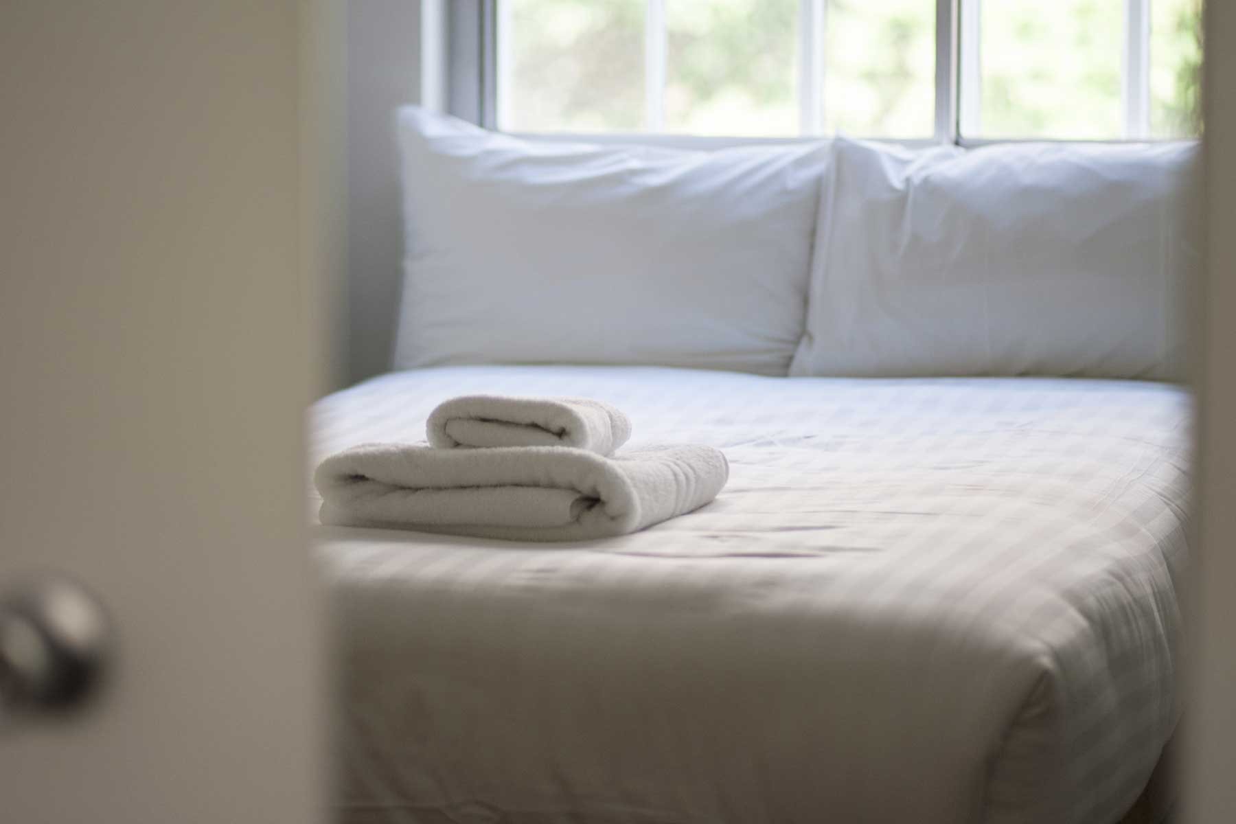 An image of a bed with sheets and towels on top.