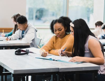 The multi-ethnic group of students work independently or together on classwork.