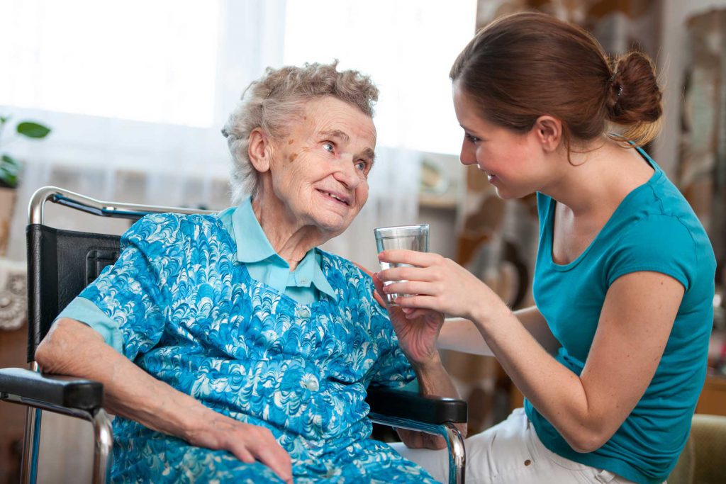 An image of a health care assistand and an elderly woman in a care home.