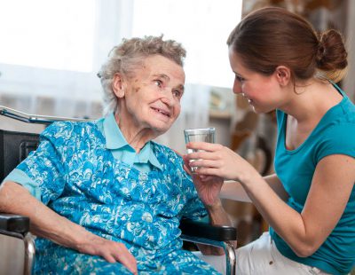 An image of a health care assistantt and an elderly woman in a care home.