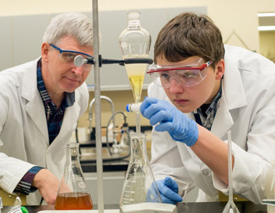 A student and instructor inside a science lab.