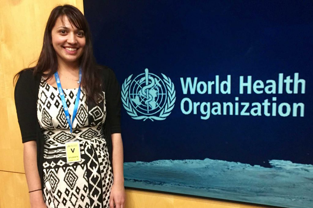 An image of a College intern standing beside a World Health Organization sign.